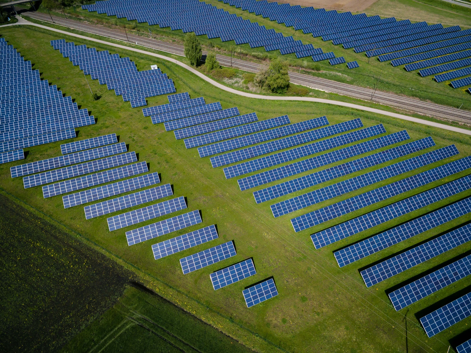 Vista aérea de uma usina solar com linhas de transmissão ao fundo